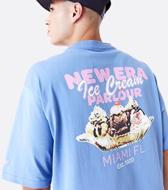 man wearing blue new era graphic t-shirt facing backwards