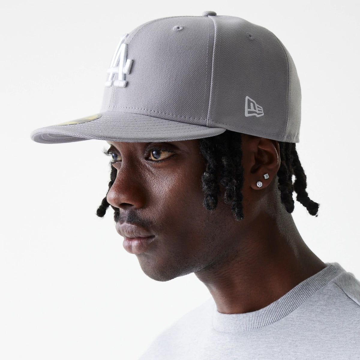 LA Dodgers MLB Basic Grey New Era 59FIFTY Fitted Cap, three-quarter view on a model showing the raised white LA logo on the front panel, New Era flag logo on the left side, and gold 59FIFTY size sticker on the grey visor.