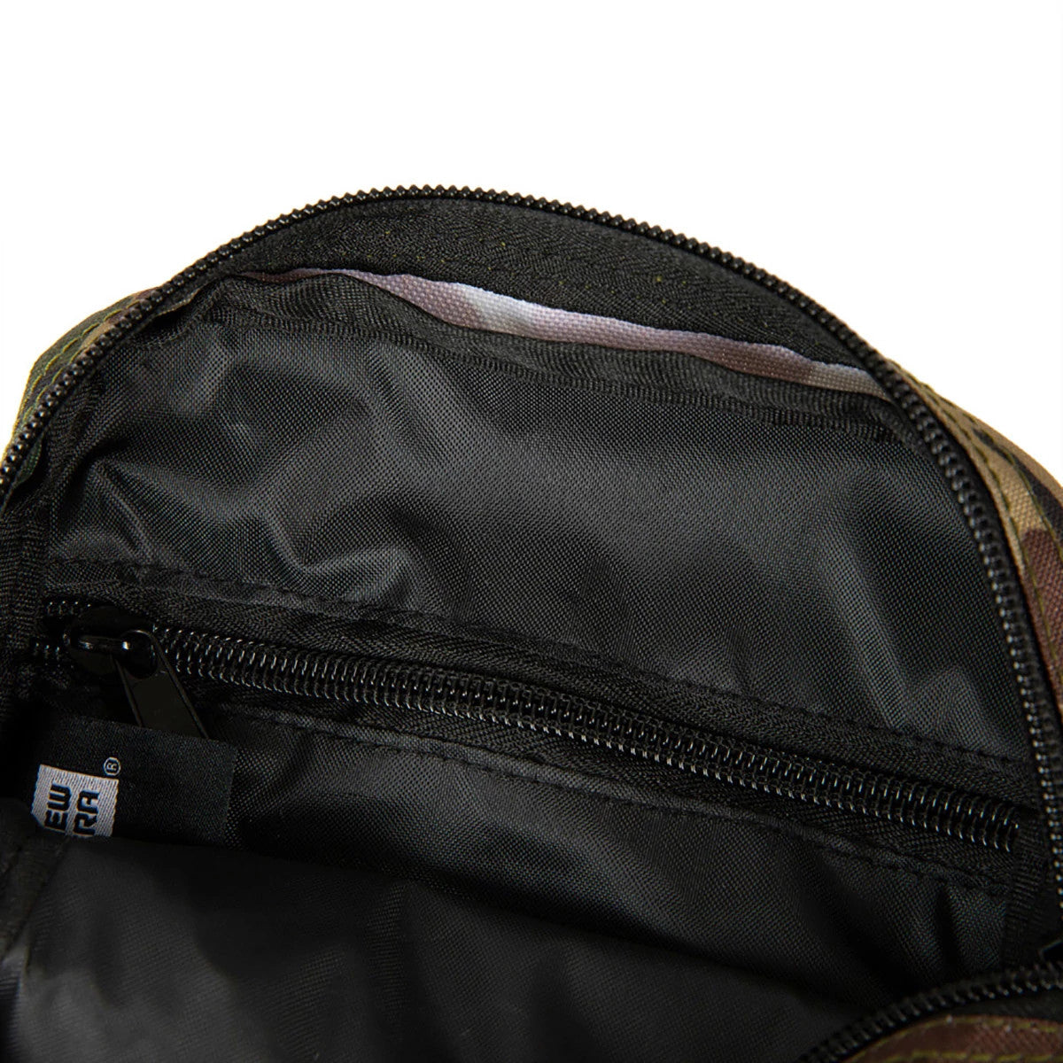 LA Dodgers Woodland Camo Side Bag, open view showing the open main compartment with a black interior, a zipped pocket on the inside back panel, and a small white New Era tag attached near the inner zip.