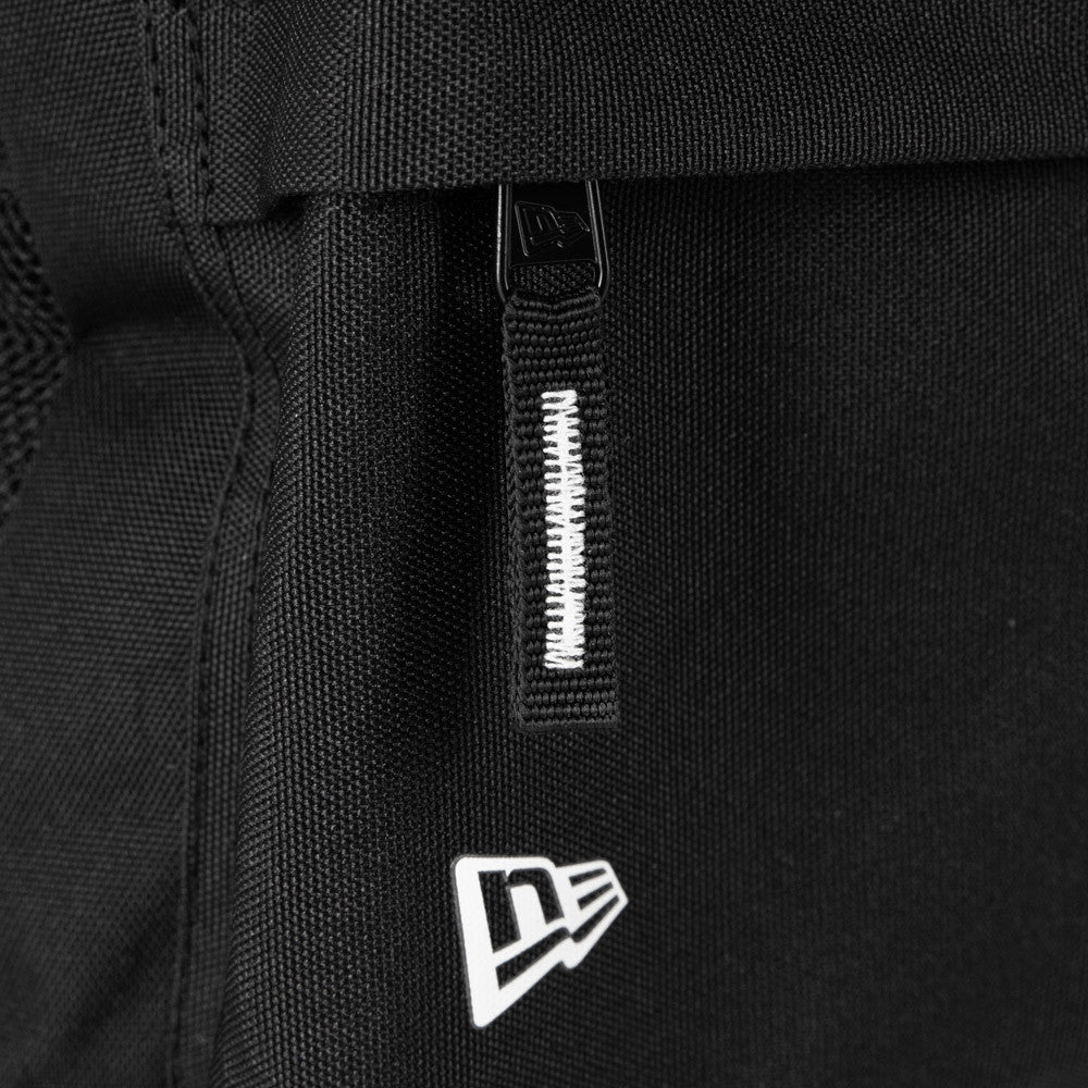 New Era New York Yankees Black Stadium Backpack, side view showing the black zip with a branded pull tab, a white raised New Era logo on the lower section, and reinforced stitching along the edges of the backpack.