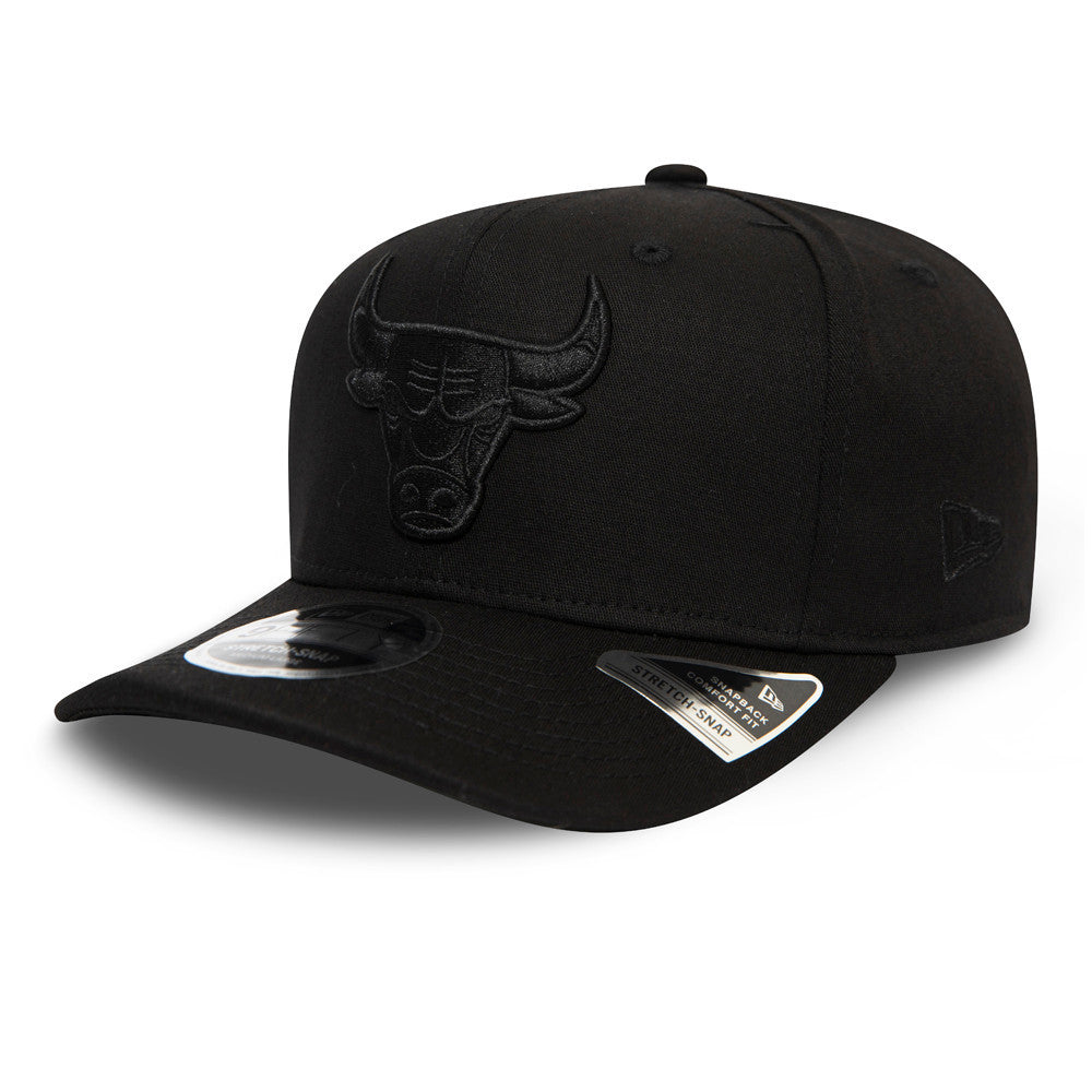 Chicago Bulls Tonal Black New Era 9FIFTY Stretch Snap Cap, three-quarter view showing the raised black embroidered Bulls logo on the front panel, curved visor with a 9FIFTY size sticker, and New Era flag logo on the left side.
