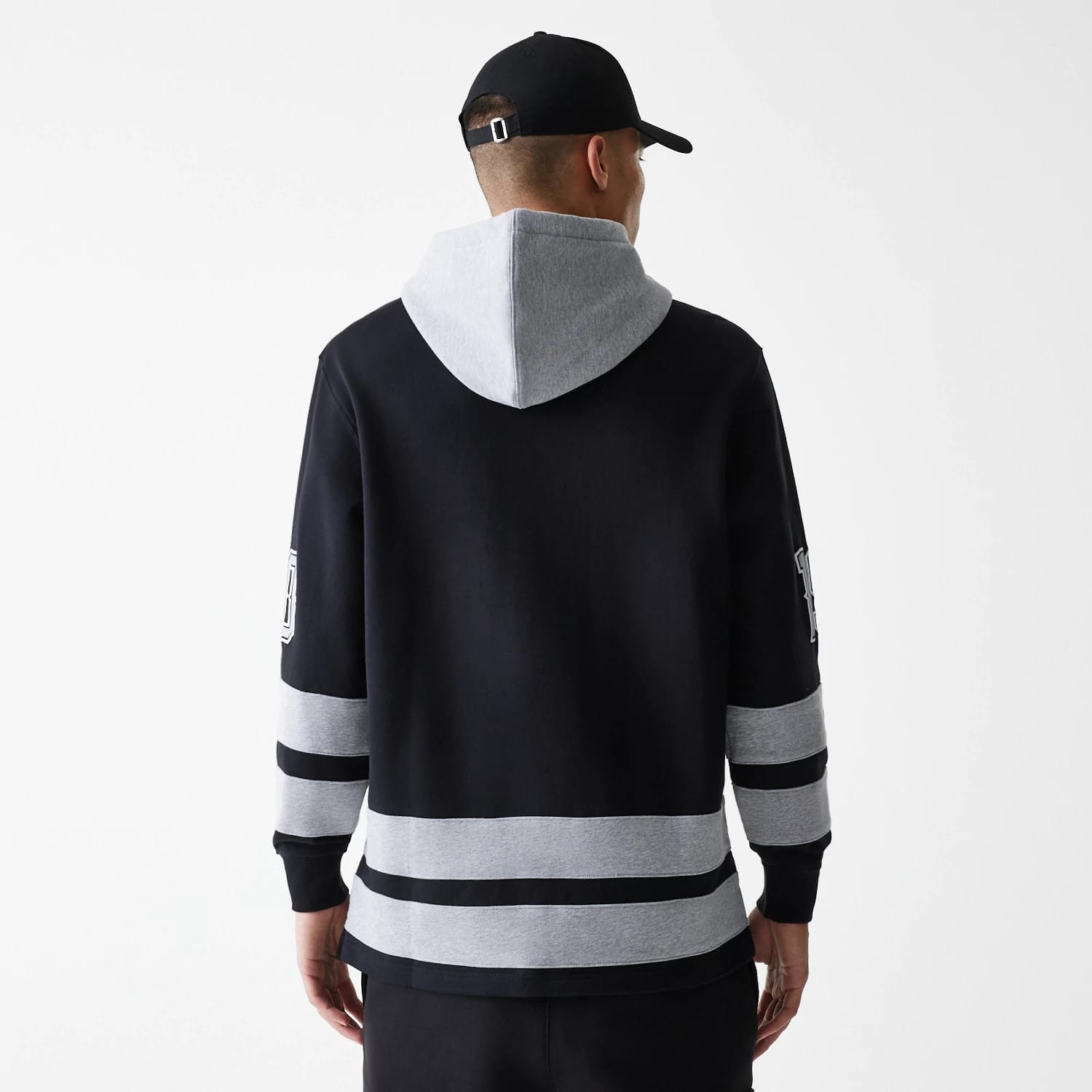 New Era Street Dangle Grey Pullover Hoodie, rear view showing a grey hood contrasted with black sleeves, grey bands around the arms and hem, and a raised logo detail on the left sleeve.