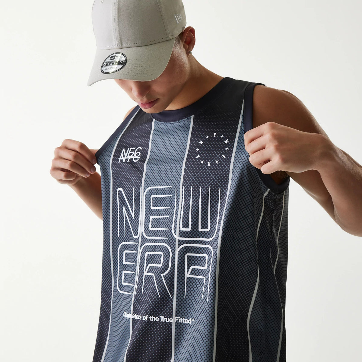 New Era City Sport Black Tank Top, on-model view with a detailed front print featuring NE6 and NEW ERA text, paired with a grey cap showing a New Era flag logo on the left side and a 9FORTY size sticker on the visor.
