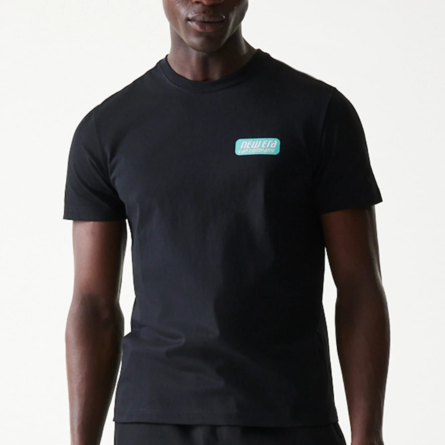 New Era Classic Black T-Shirt, front view showing a black short-sleeved design with a green and white embossed New Era logo patch on the left chest, crew neckline and straight hem.