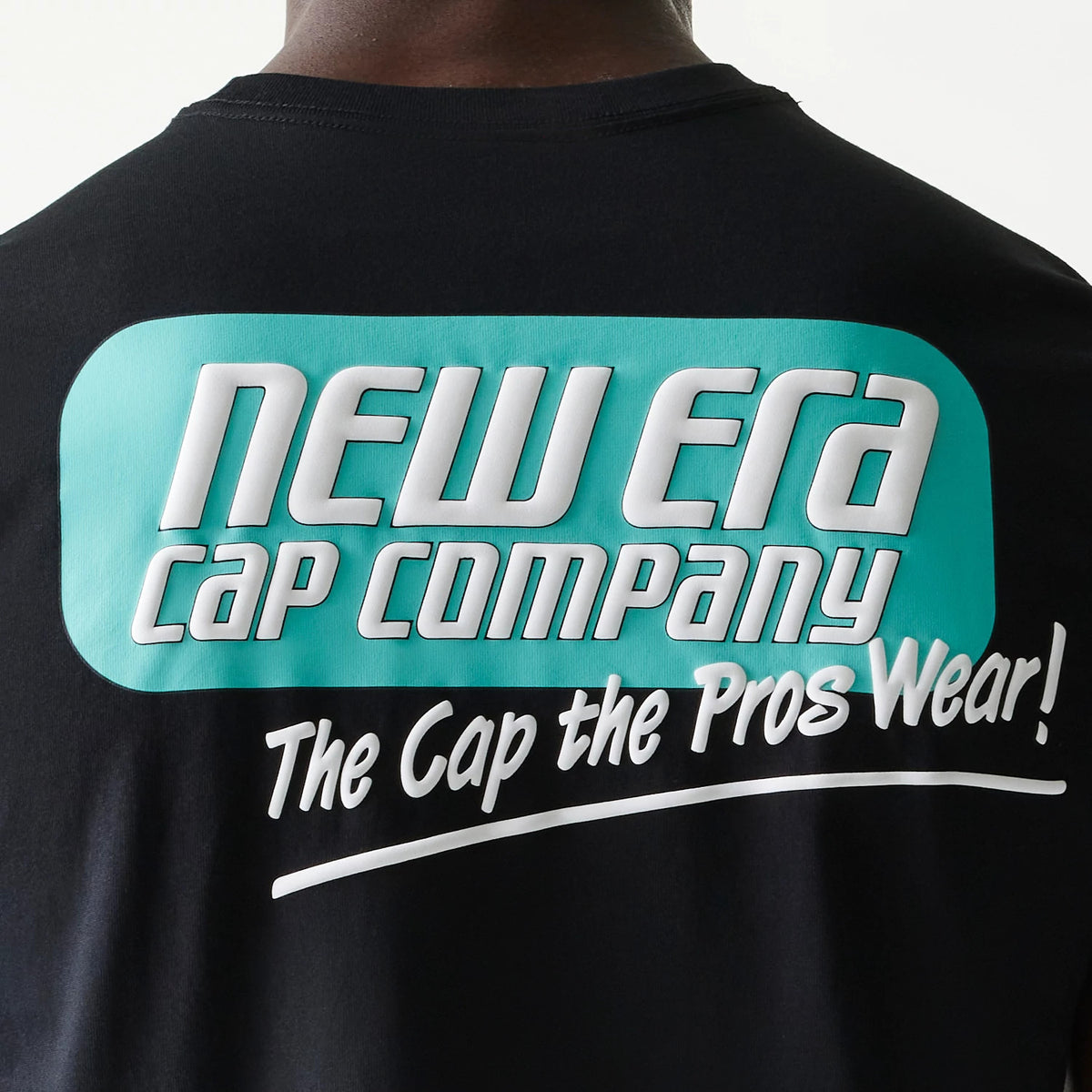 New Era Classic Black T-Shirt, rear view showing the black fabric with a large turquoise and white printed logo that reads "New Era Cap Company" across the upper back, accompanied by "The Cap the Pros Wear!" in white below.