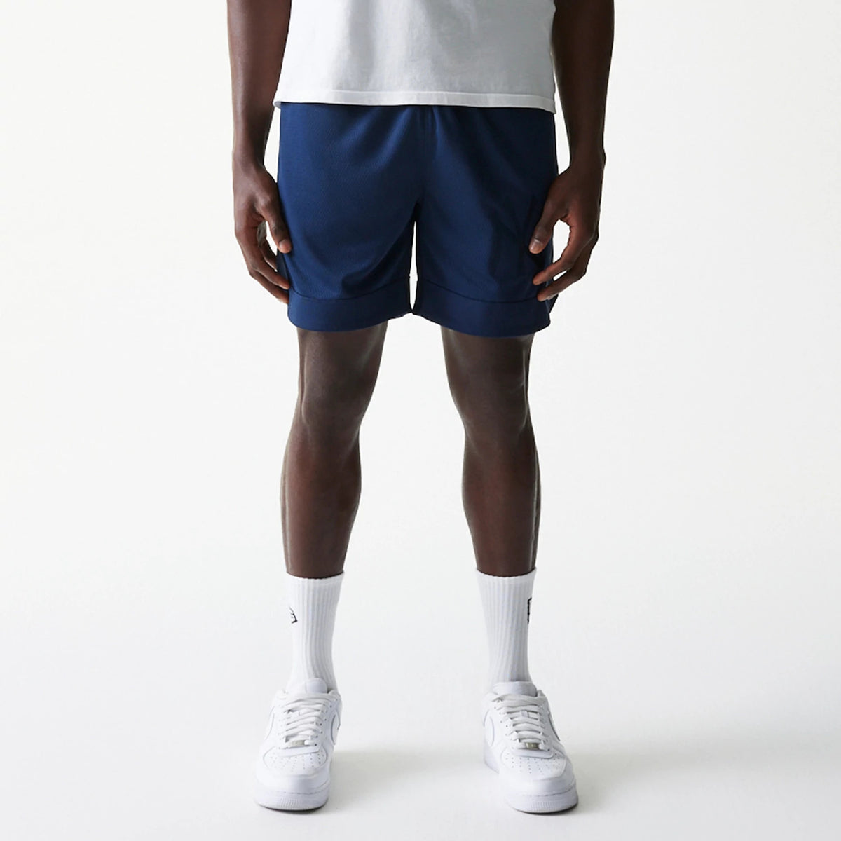 New Era New York Yankees Tonal Pack Blue Shorts, front view showing the deep blue shorts with a straight hem above the knee, worn by a model standing in white socks and trainers, simple design without any visible logos or patterns.