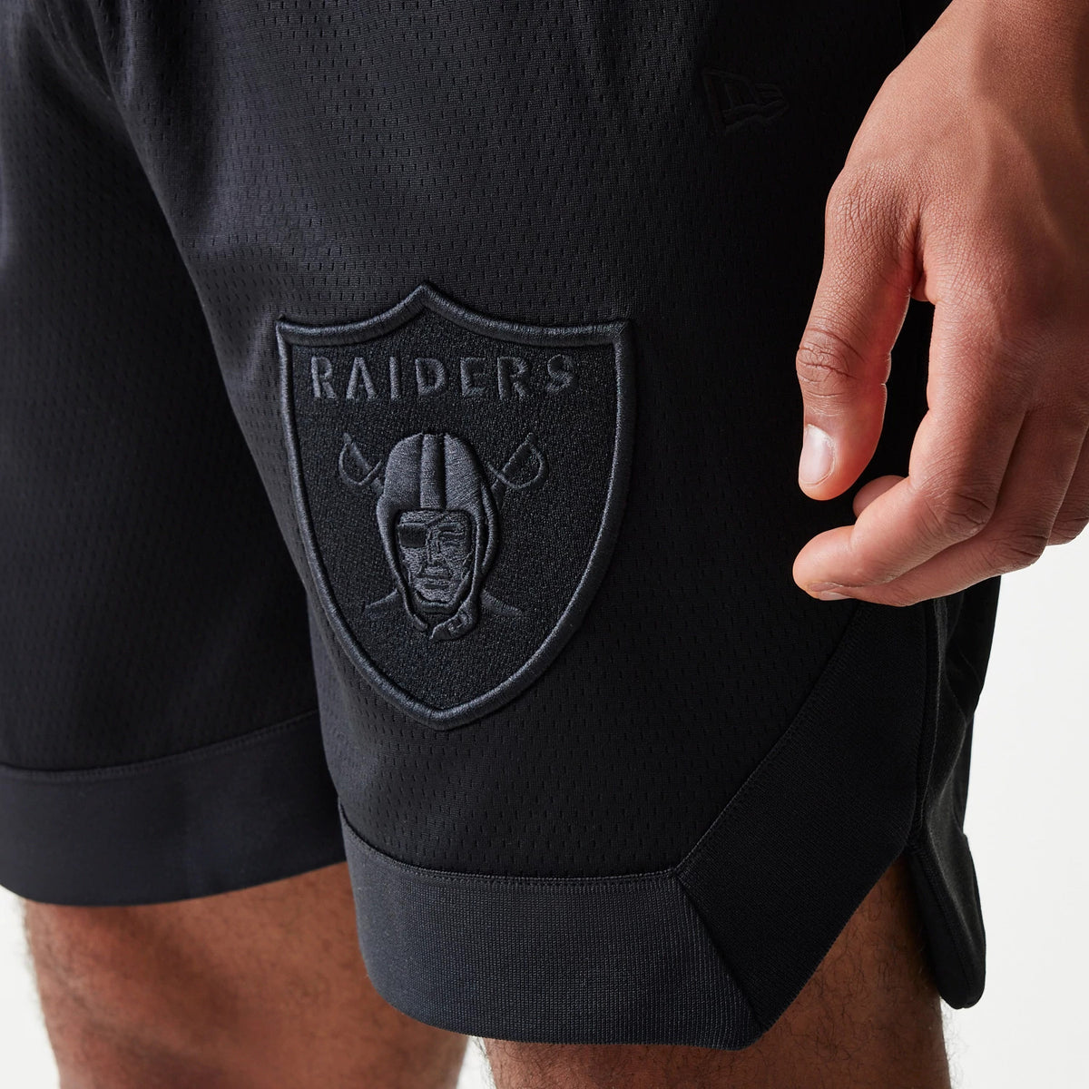 New Era Las Vegas Raiders Tonal Pack Black Shorts, front view showing a raised Raiders shield logo on the left leg, textured black fabric, and the New Era flag debossed near the pocket.