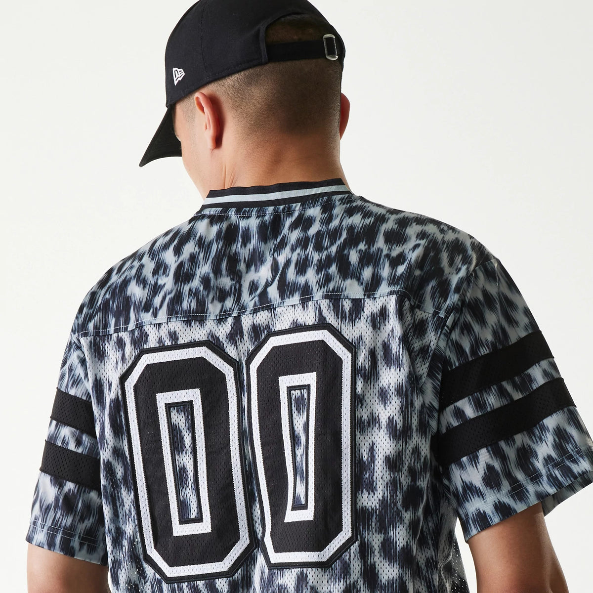 New Era Retro Sports Grey Mesh Jersey, back view on a model wearing a black cap, showcasing large white and black number 00 embroidery on the speckled grey mesh fabric with black striped sleeves.