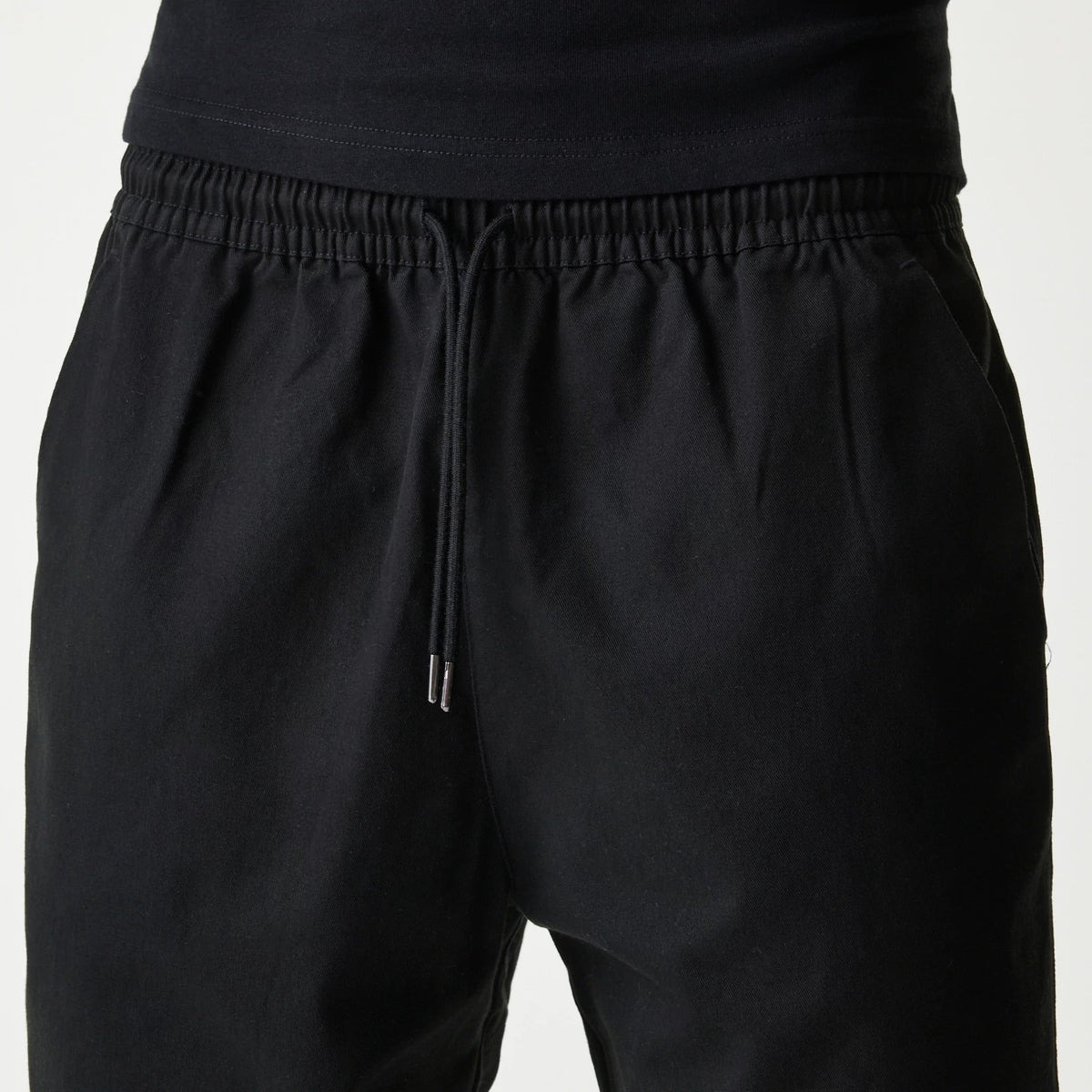 New Era Japan Woven Black Shorts, front view showing the black shorts with an elastic waistband and adjustable drawstring, subtle side pockets and a relaxed fit around the waist and hips.