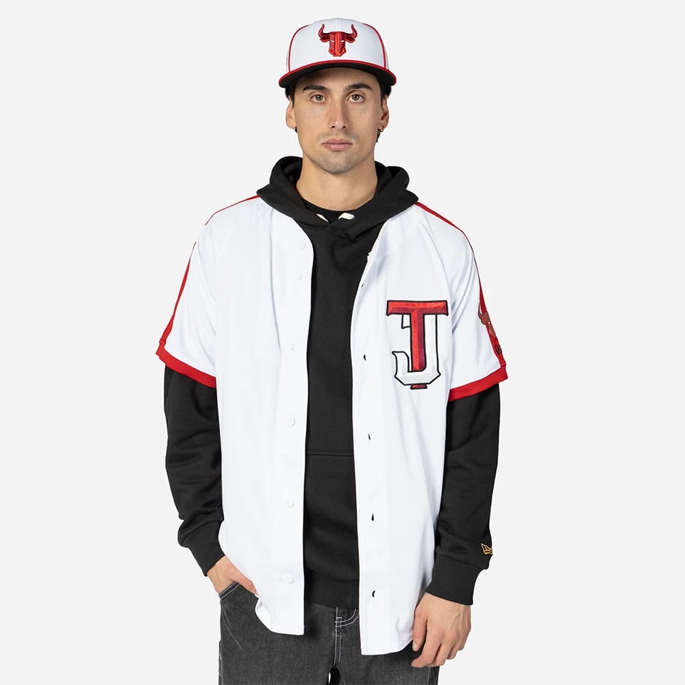 Tijuana Toros Mexico LMB On Field White On-Field Jersey, on-model view with a red T logo on the left chest and a cap showing the team emblem, styled over a black hoodie with red trim detailing on the sleeves.