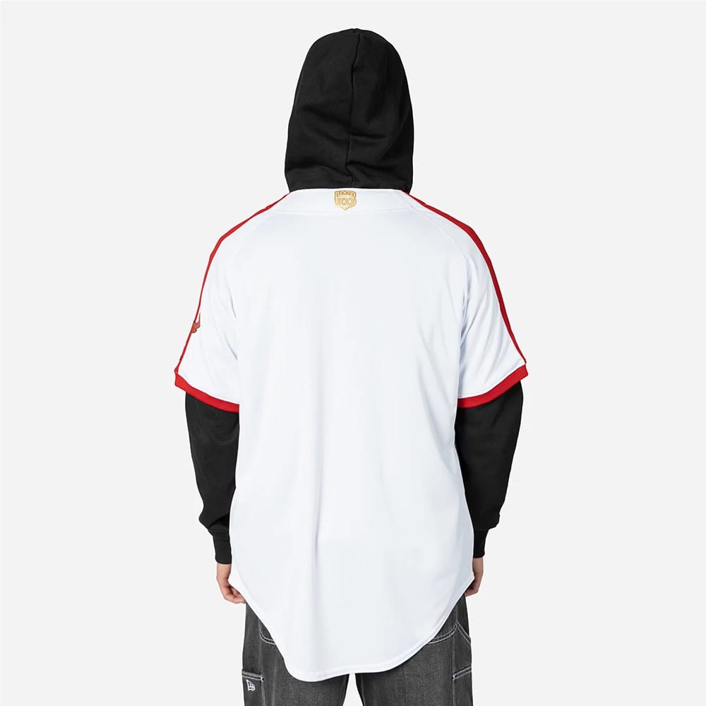 Tijuana Toros Mexico LMB On Field White On-Field Jersey, back view on a model wearing a black hoodie underneath, showing the golden Toros logo beneath the collar and the red and black sleeve detailing.