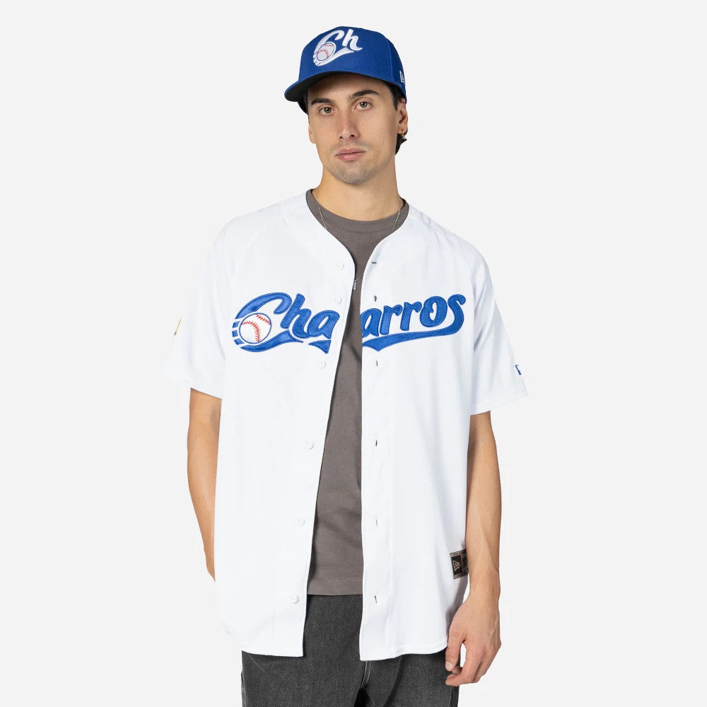 Charros De Jalisco Mexico LMB On Field White On-Field Jersey, front view on a model wearing a matching blue cap with “Ch” logo, showcasing the blue embroidered Charros script on the chest.