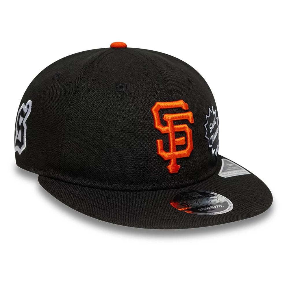 San Francisco Giants MLB X Saint Mxxxxxx Black Retro Crown New Era 9FIFTY Snapback Adjustable Cap, three-quarter view showing raised orange SF logo on front panel, white Saint Mxxxxxx graphic on right side, and 9FIFTY sticker on the black visor.