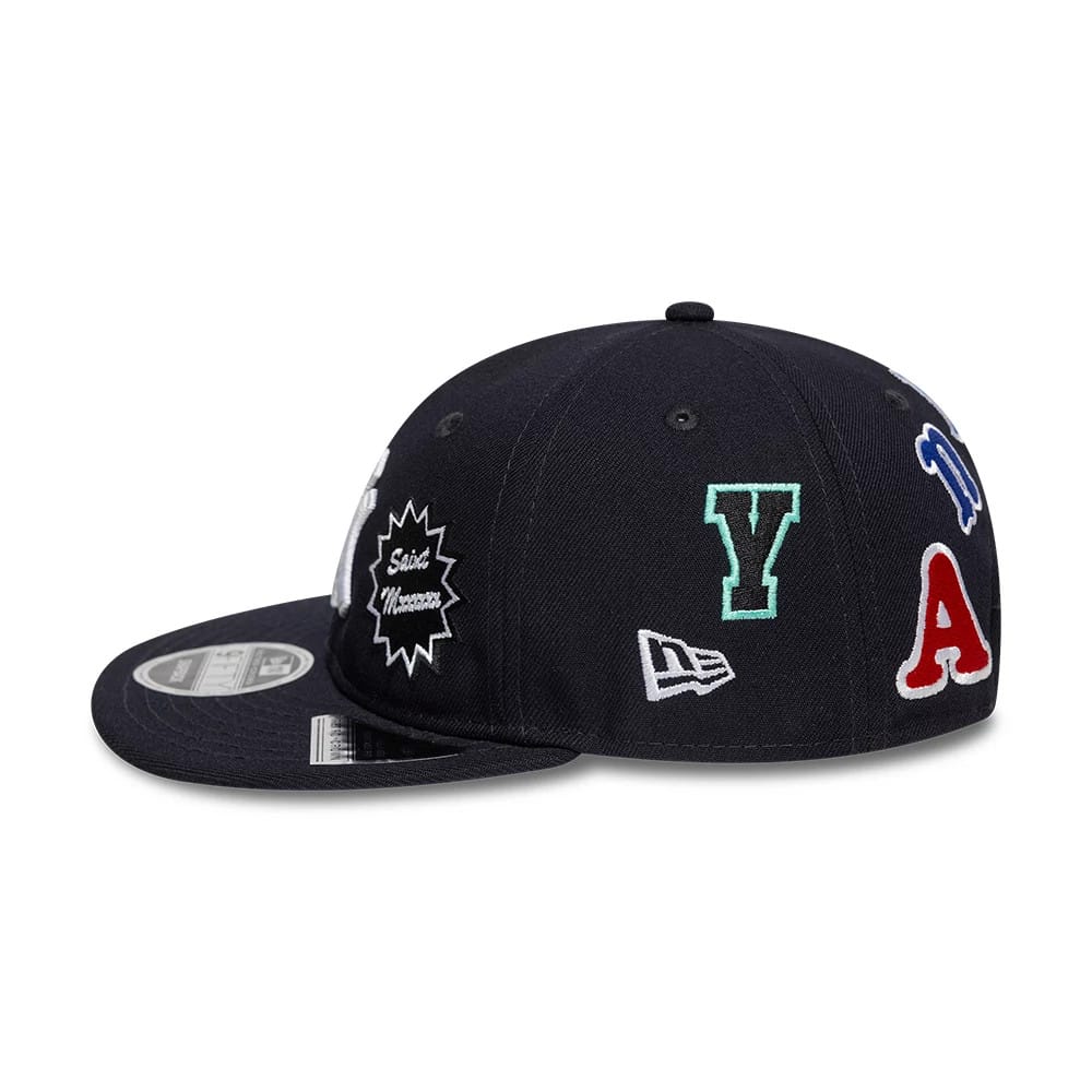 New York Yankees MLB X Saint Mxxxxxx Navy Retro Crown New Era 9FIFTY Snapback Adjustable Cap, side view with multicoloured embroidered logos including the Y and A logos and the New Era flag logo on a structured navy crown.