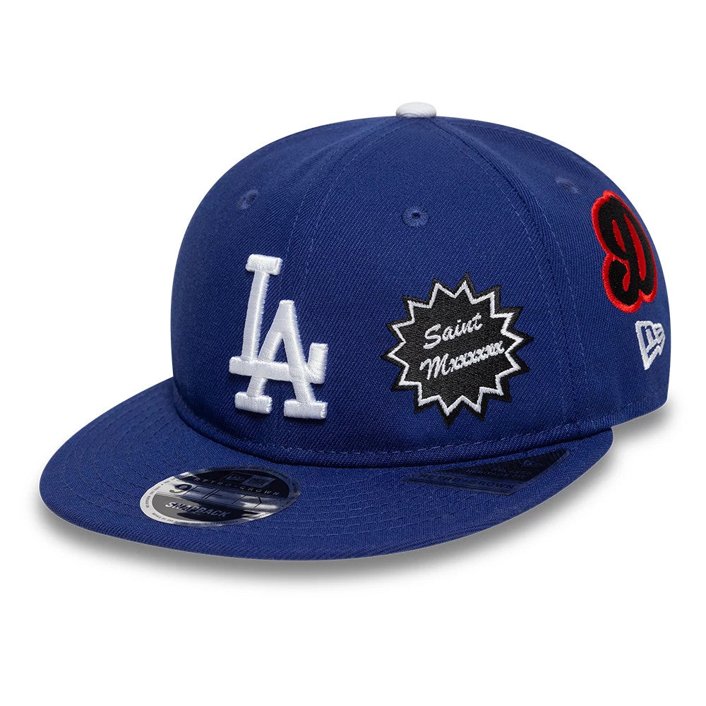 LA Dodgers MLB X Saint Mxxxxxx Dark Blue Retro Crown New Era 9FIFTY Snapback Adjustable Cap, three-quarter view showing white raised LA logo on the front panel, black and white patch with Saint Mxxxxxx lettering, and red embroidery on the left side.