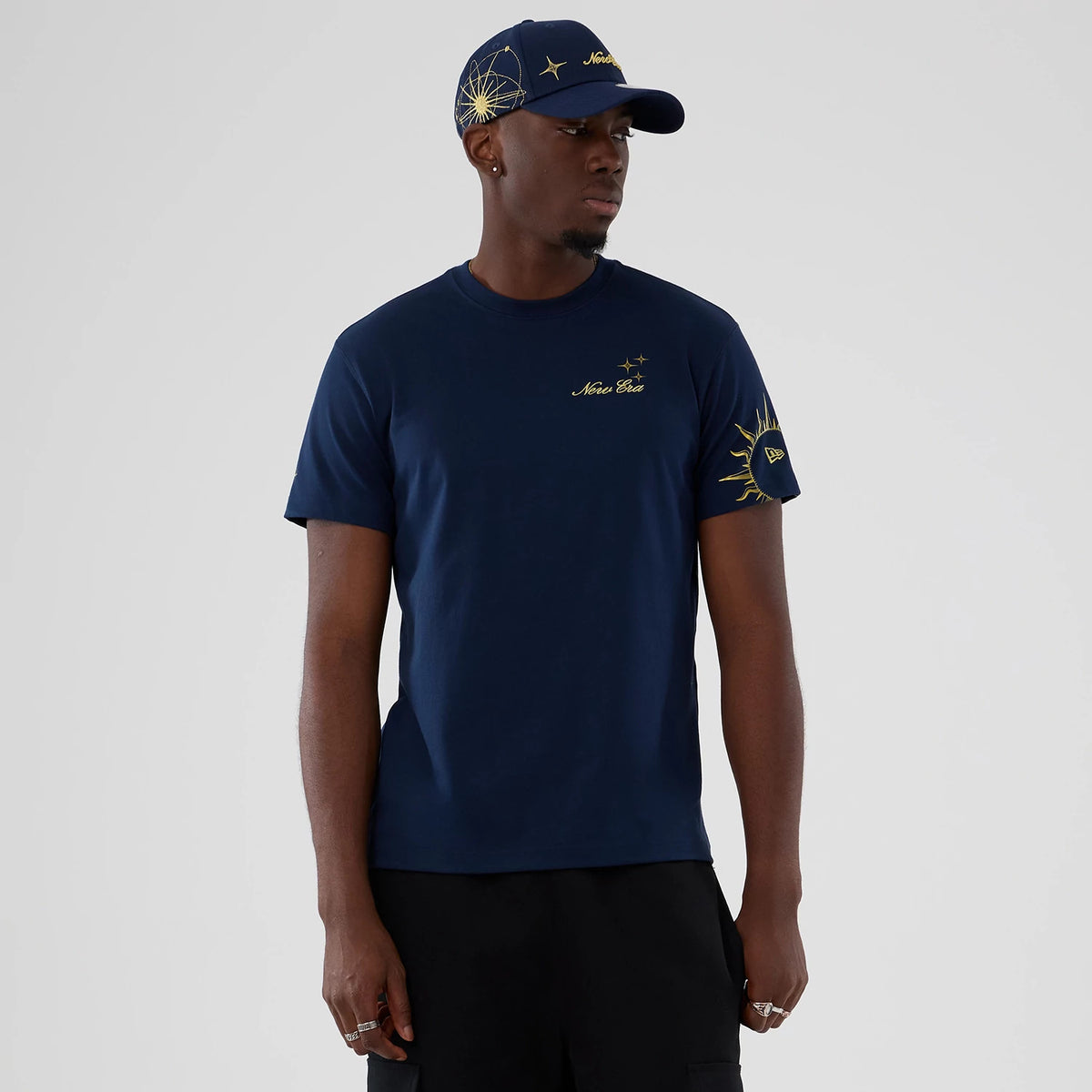 New Era Cosmic Craft Blue T-Shirt, on-model view showing a deep blue colour with yellow graphics on the chest and right sleeve, paired with a matching cap featuring a raised logo on the front and a large graphic on the side.