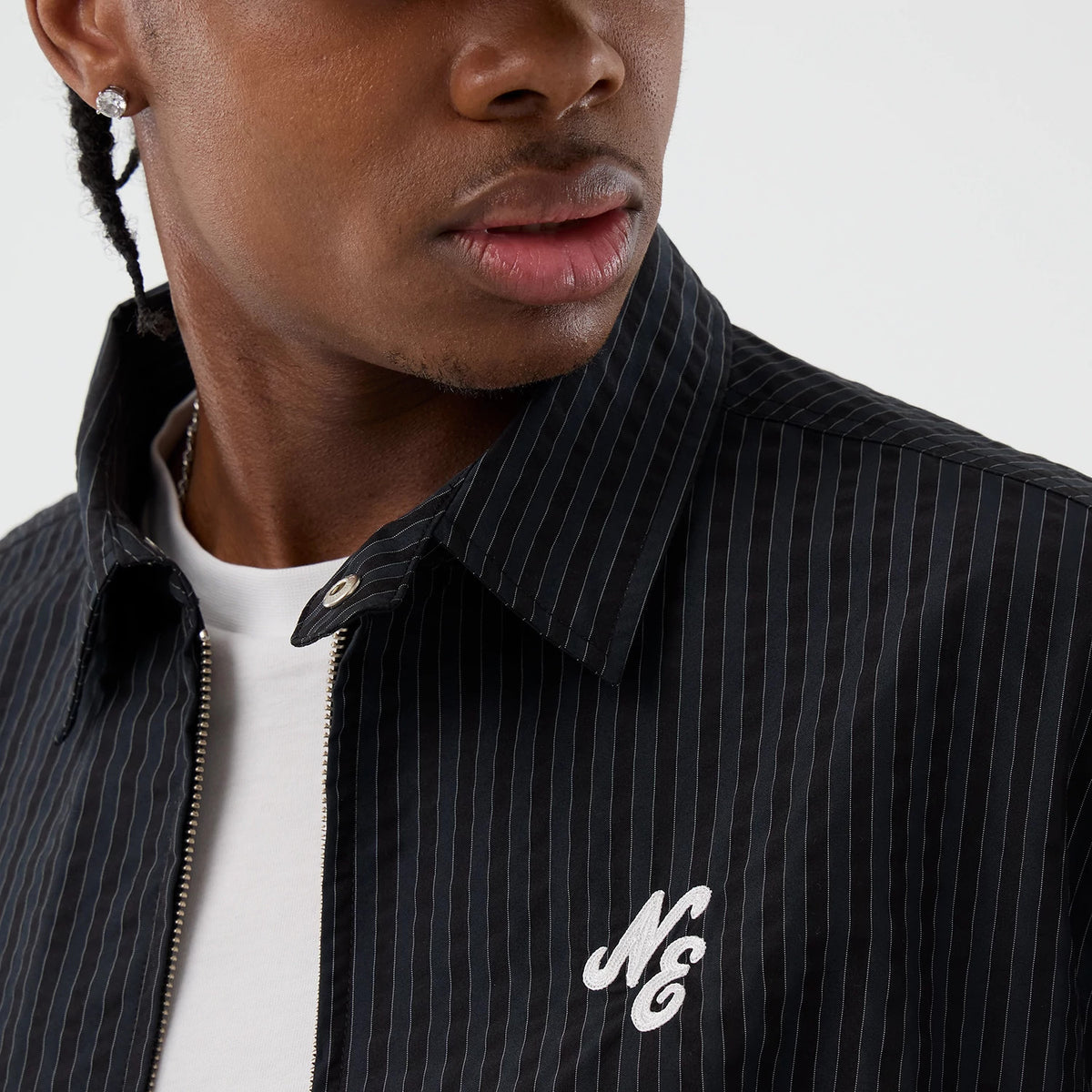 New Era Street Class Navy Jacket, three-quarter view showing the dark navy fabric with subtle pinstripes, a raised embroidered logo on the left chest and a partially visible zip closure at the front.
