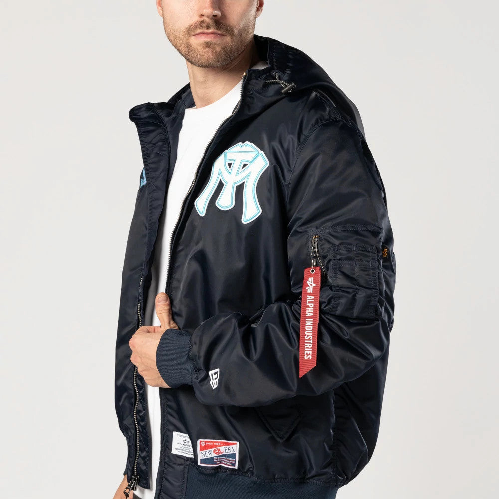 Sultanes De Monterrey LMB X Alpha Navy Jacket, front view showing a large white and blue embroidered logo on the chest, a zip closure, a red Alpha Industries tag on the sleeve, and the New Era logo embroidered near the cuff.