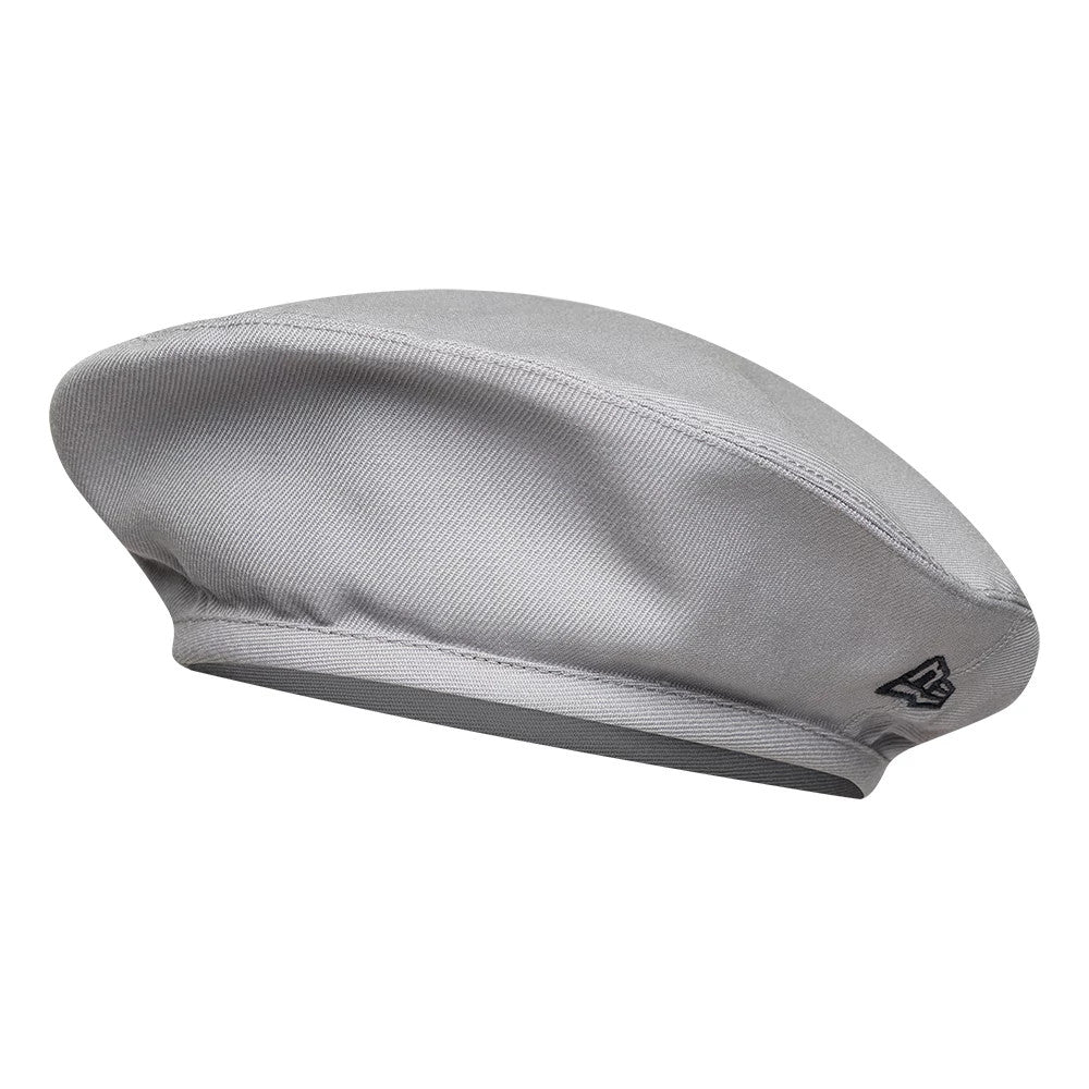New Era Wool Grey Beret, side view showing the black embroidered New Era flag logo on the side, with a smooth grey crown and a subtle soft edge where the rim curves.
