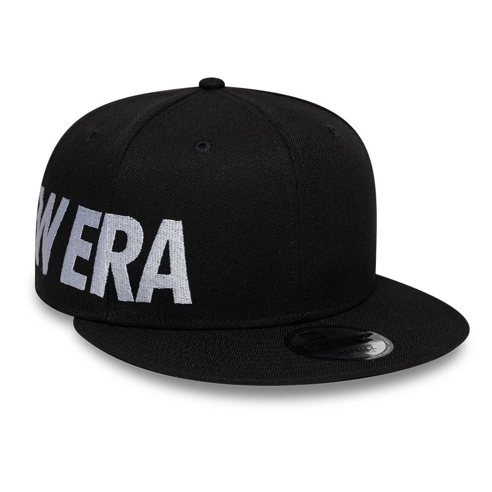 New Era Essential Black New Era 9FIFTY Snapback Adjustable Cap, three-quarter view showing raised white "New Era" embroidery across the front panel and right side, with a black flat visor featuring a 9FIFTY size sticker.