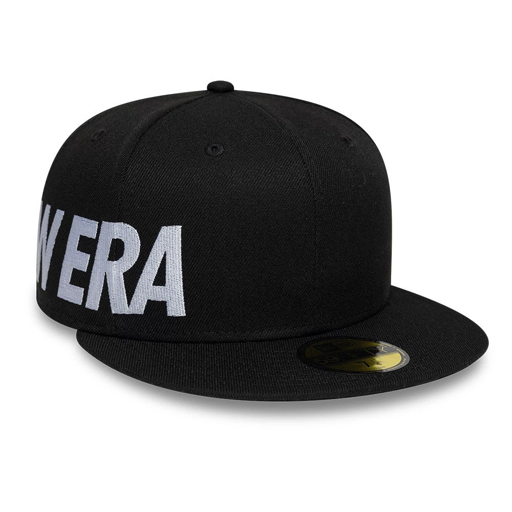 New Era Side Hit Black New Era 59FIFTY Fitted Cap, side view with raised white embroidered New Era lettering on the left panel, featuring a flat black visor with a gold 59FIFTY size sticker on top.