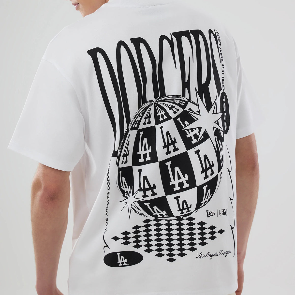 LA Dodgers MLB White T-Shirt, rear view showing a large black and white checkered globe graphic with LA logos, bold "DODGERS" text above, and smaller New Era and MLB logos near the bottom.