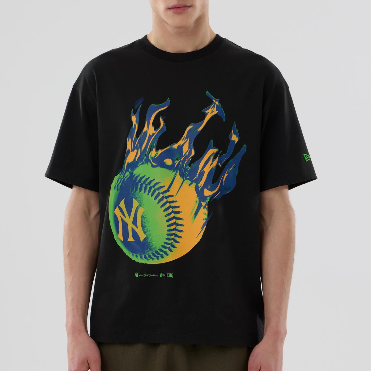 New York Yankees MLB On Fire Black Oversized T-Shirt, front view showing a large flaming baseball graphic with the yellow NY logo on the chest and a small green embroidered New Era logo on the left sleeve.