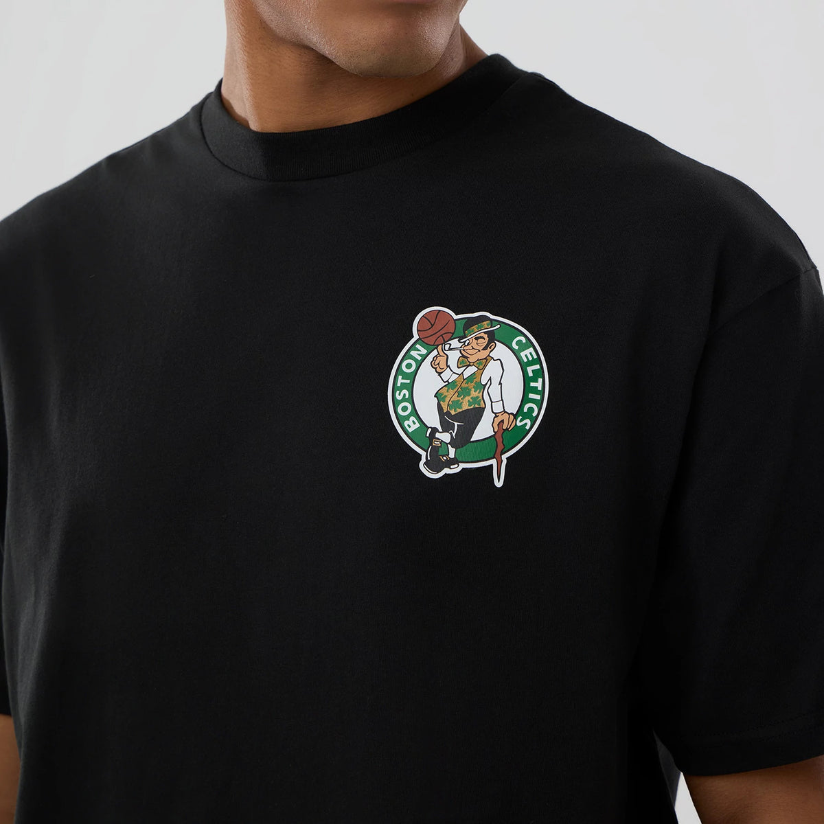 Boston Celtics NBA logo Black T-Shirt, front view showing the colourful team logo prominently printed on the left chest of the plain black fabric, with a ribbed collar around the neck.
