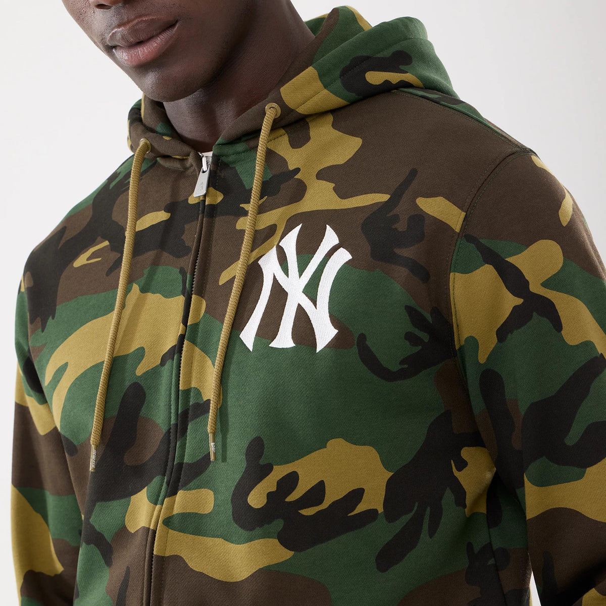 New York Yankees MLB Woodland Camo 2 Way Full Zip Hoodie, front view showing the green and brown camouflage pattern with a white embroidered New York Yankees logo on the left chest and mustard drawstrings attached to the hood.