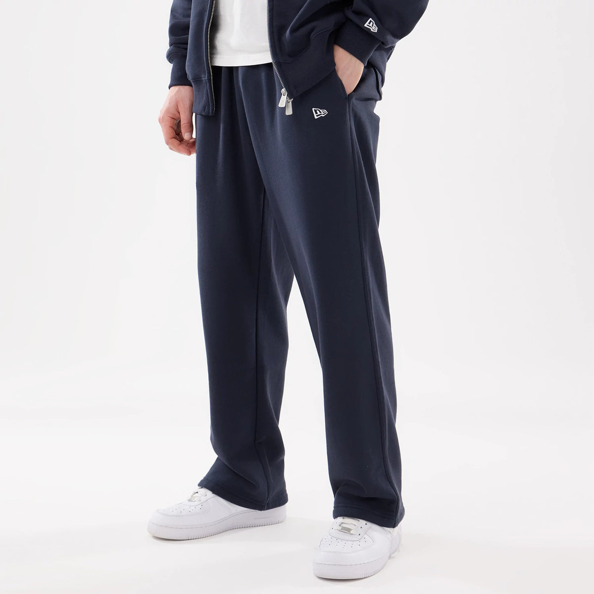 New York Yankees MLB Comfort Blue Joggers, on a model with a matching blue zip-up hoodie, featuring white New Era flag logos on the upper left leg and left sleeve, styled with white sneakers and a casual stance.