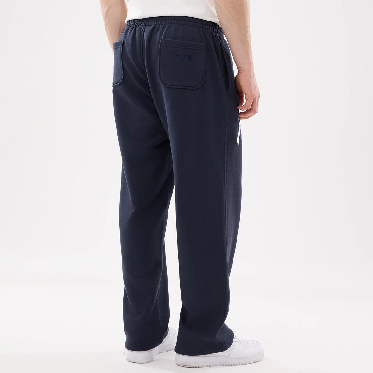 New York Yankees MLB Comfort Blue Joggers, rear view on a model showing embroidered logos on the back pocket, with an elastic waistband and straight-leg fit, paired with white trainers and a white T-shirt.