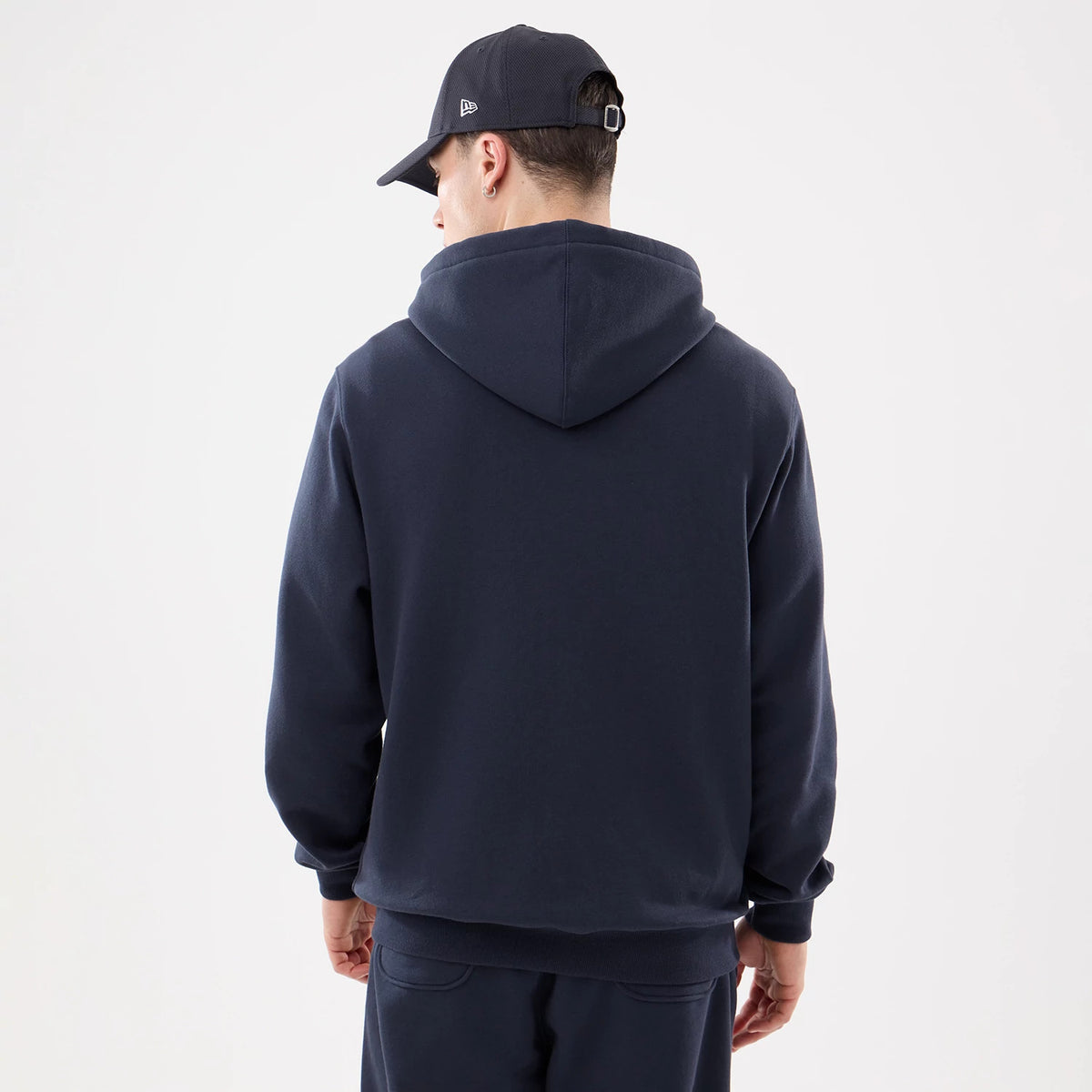 New York Yankees MLB Comfort Navy 2 Way Full Zip Hoodie, rear view showing the navy hoodie with a relaxed fit and large hood, on a man wearing a black cap with a raised New Era logo on the side.