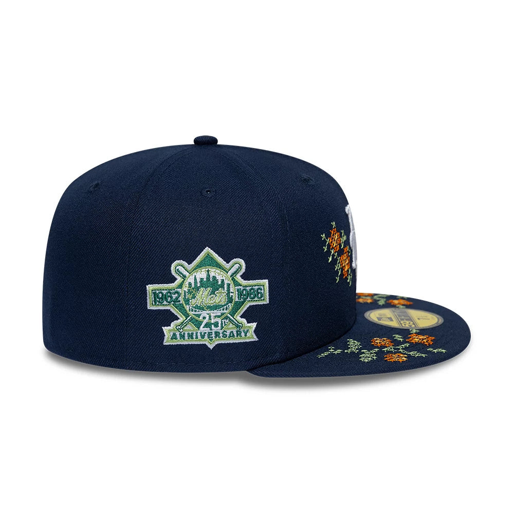 New York Mets MLB Garden Dark Blue New Era 59FIFTY Fitted Cap, side view showing the embroidered 25th anniversary logo on the right panel and a gold 59FIFTY size sticker on the dark blue visor with floral accents.