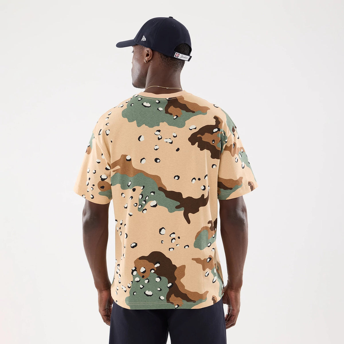 New York Yankees MLB Camo Desert Camo T-Shirt, on-model rear view showing beige background with green, brown, and black camouflage pattern, short sleeves, and a navy cap featuring a raised logo on the side.