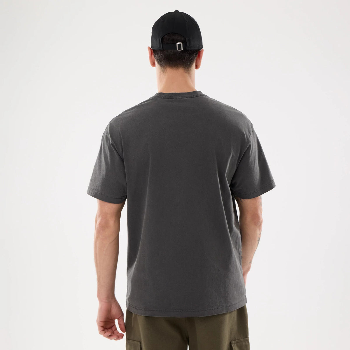 Chicago Bulls NBA Shadow Pop Black T-Shirt, rear view showing the plain black back with no visible logos or designs, worn by a person also wearing a plain black cap with a metal clasp on the strap.
