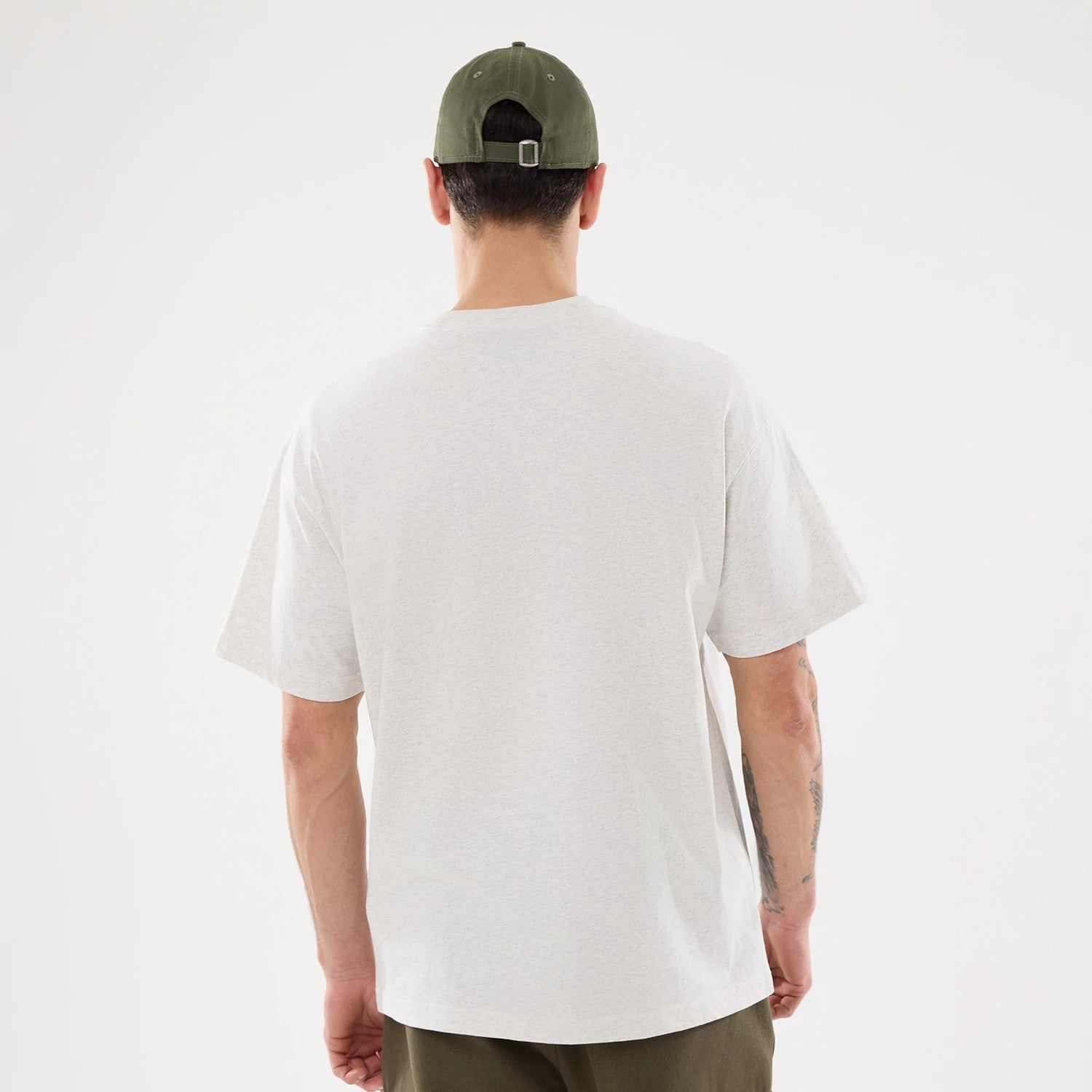 LA Dodgers MLB Comfort Grey T-Shirt, rear view showing the plain light grey fabric extending across the back with short sleeves, worn by a person also wearing a green cap with eyelets and a metal clasp at the back.