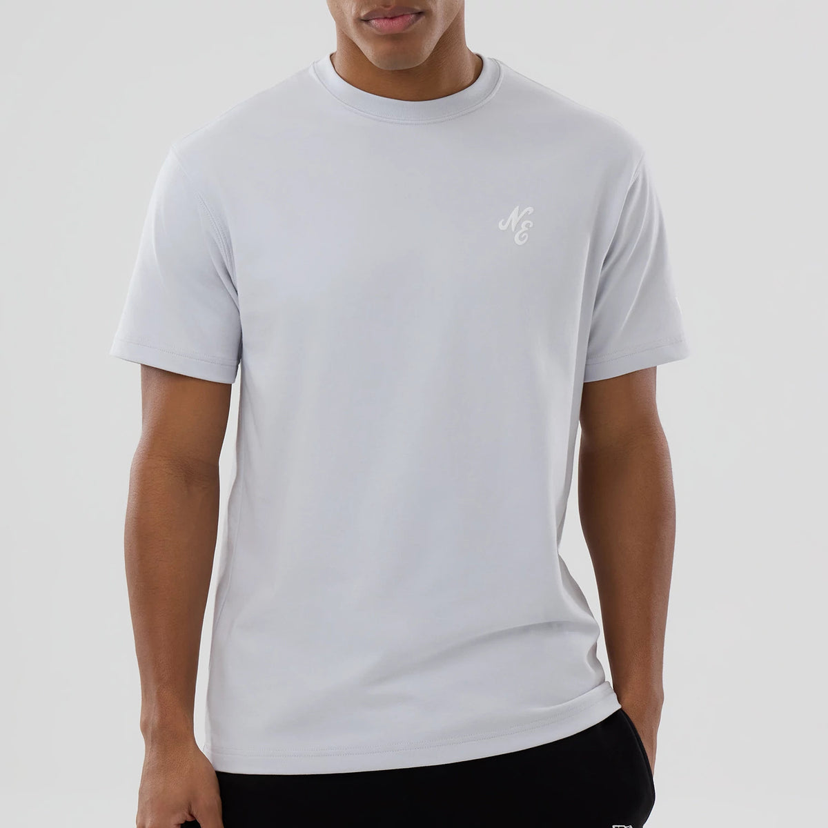 New Era Zodiac Sign Silver T-Shirt, front view showing a silver short-sleeve shirt with a small white embroidered "NE" logo on the left chest, ribbed neckline, and smooth fabric surface.