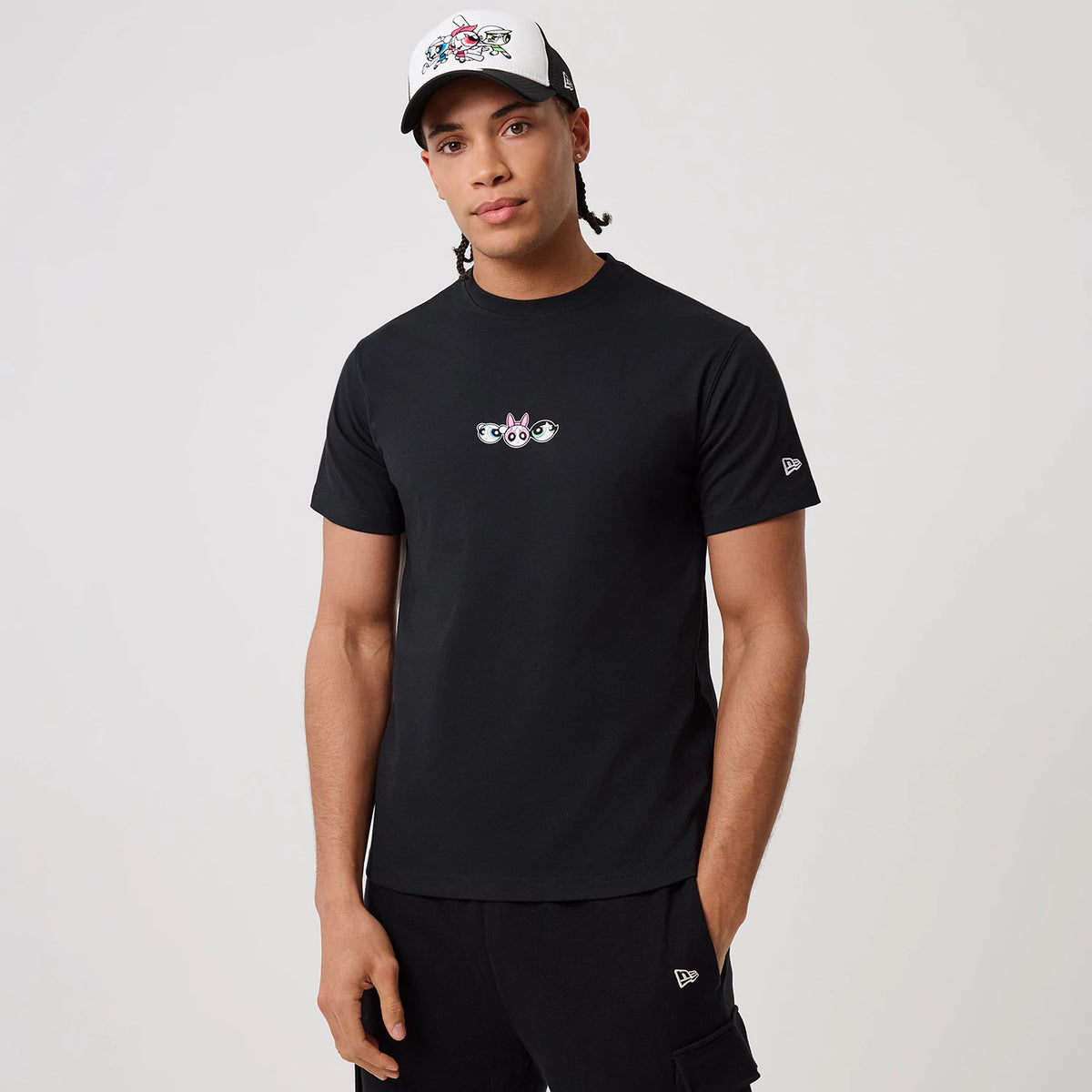 Powerpuff Girls Powerpuff Girls Black T-Shirt, on-model view showing a black T-shirt with an embroidered Powerpuff Girls logo on the chest, a debossed New Era logo on the left sleeve, paired with black shorts and a cap with a matching design on the front.