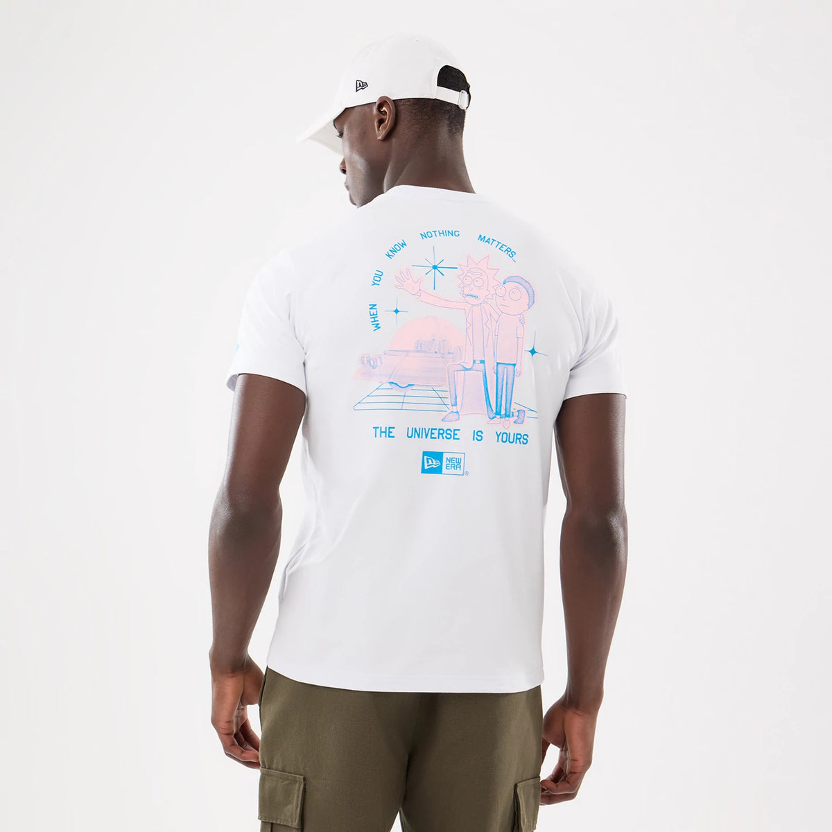 Rick And Morty White T-Shirt, rear view showing a colourful graphic of Rick and Morty with the text "THE UNIVERSE IS YOURS" on the back, worn by a model with a white cap featuring a debossed logo on the side.
