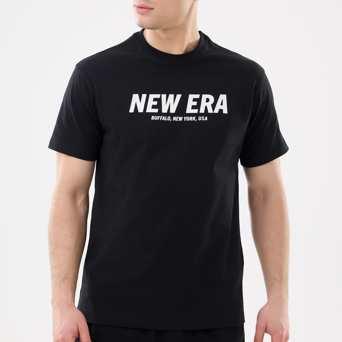 New Era Basic Black T-Shirt, on-model view showing a black T-shirt with a white printed New Era logo across the chest, "BUFFALO, NEW YORK, USA" written beneath, and short sleeves extending to the mid-arm.