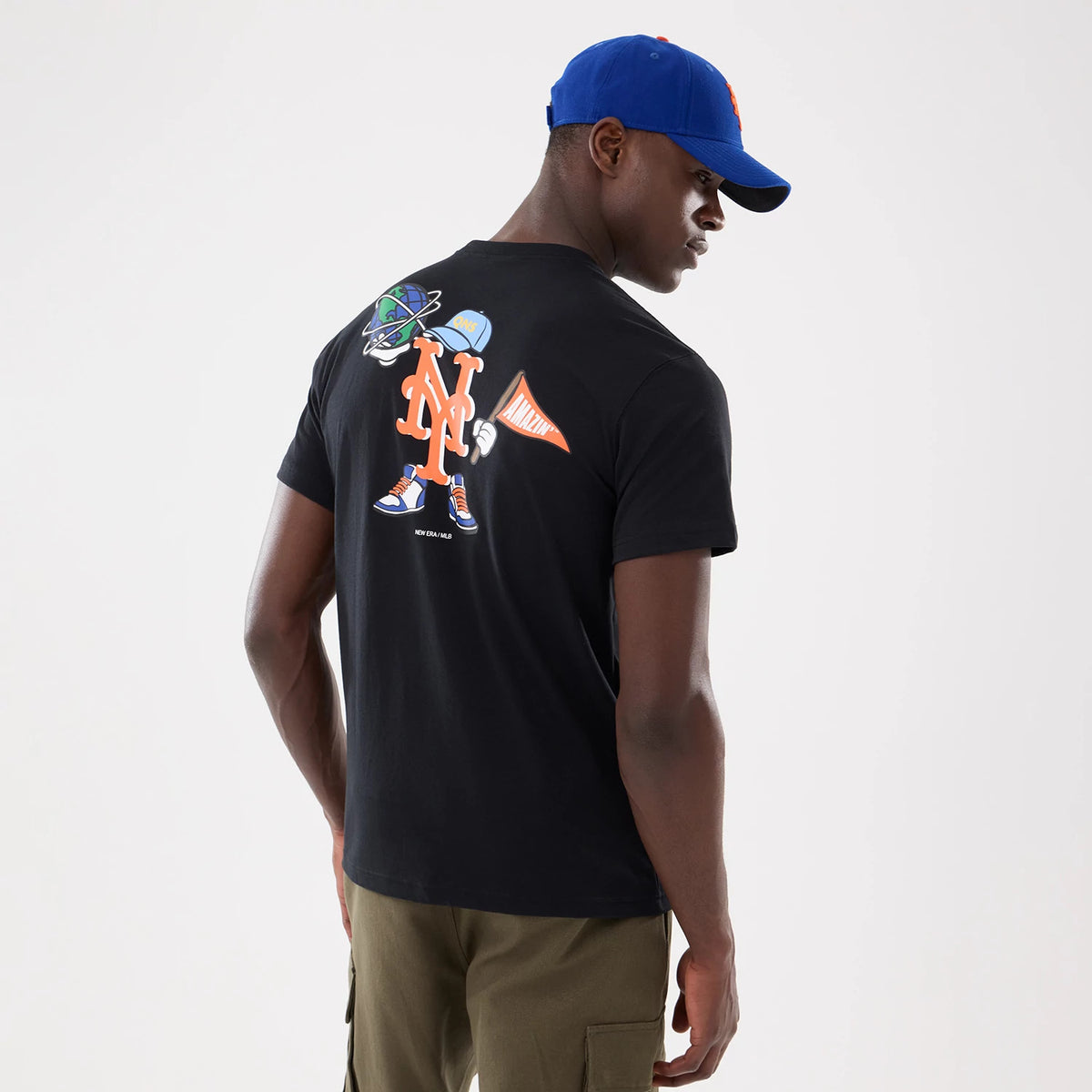 New York Mets MLB Cartoon Black T-Shirt, on-model view showing the back with a large cartoon graphic featuring the New York Mets logo in orange, a character in a cap and sneakers, and an orange pennant with "Mets" text.