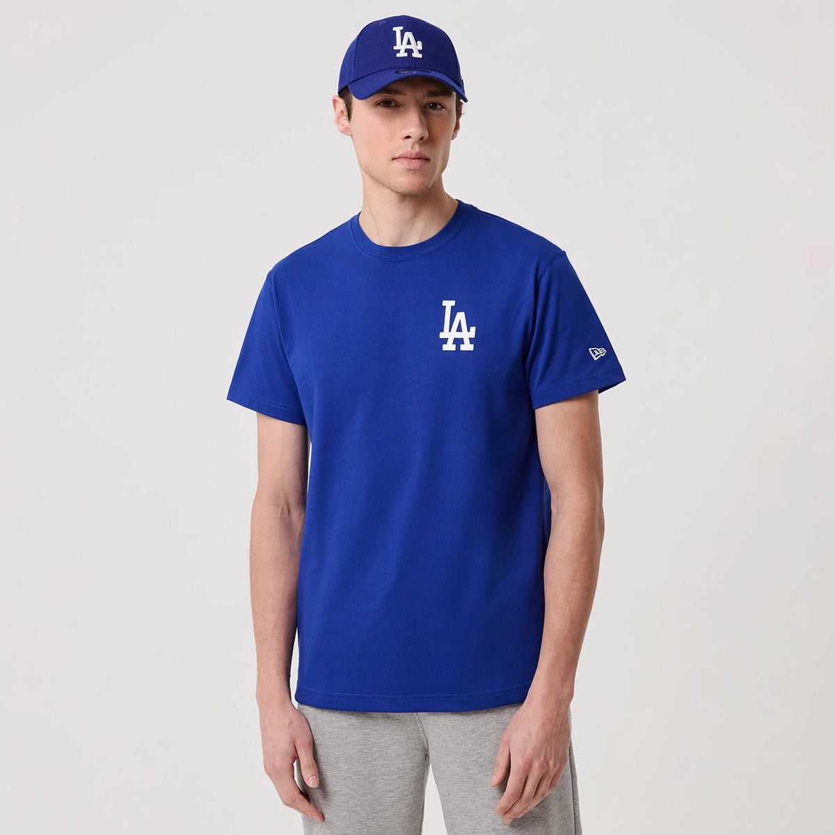 LA Dodgers MLB Banana Graphic Bright Blue T-Shirt, front view showing the blue T-shirt with a white LA logo printed on the left chest, worn by a model with a matching cap featuring an embossed LA logo and a New Era logo on the sleeve.