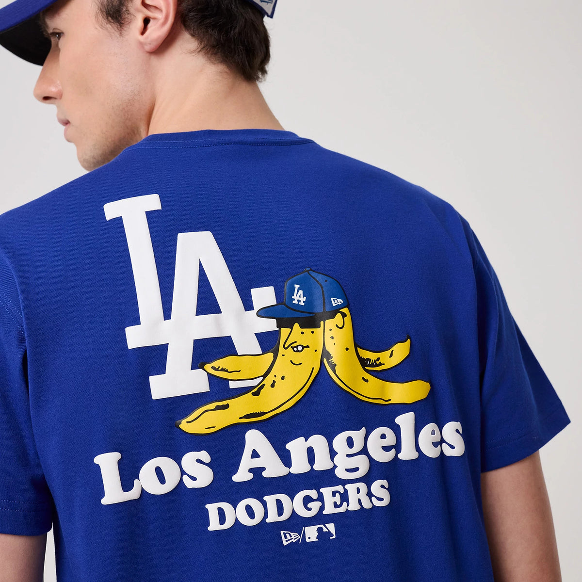 LA Dodgers MLB Banana Graphic Bright Blue T-Shirt, rear view showing a large white LA logo next to a graphic of two yellow bananas wearing a blue LA cap, with white 'Los Angeles Dodgers' text and MLB logos at the bottom.