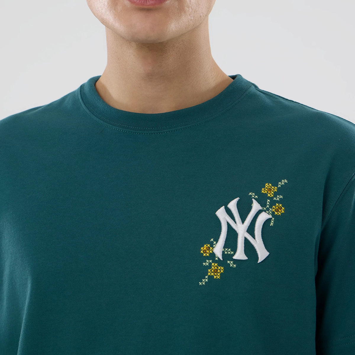 New Era New York Yankees MLB Garden Dark Green T-Shirt, on-model view showing the dark green fabric with a raised white Yankees logo on the left chest, highlighted by an embroidered floral pattern in yellow and green.