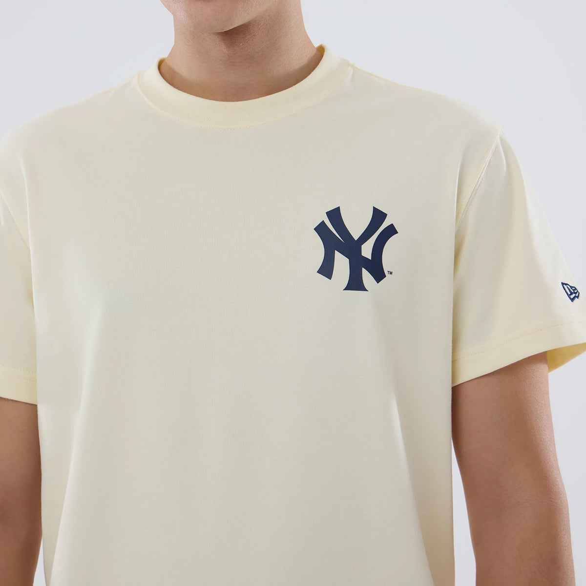 New York Yankees MLB City Series Cream T-Shirt, front view showing the cream T-shirt with a bold navy Yankees logo on the chest and a small embroidered New Era logo on the left sleeve near the hem.