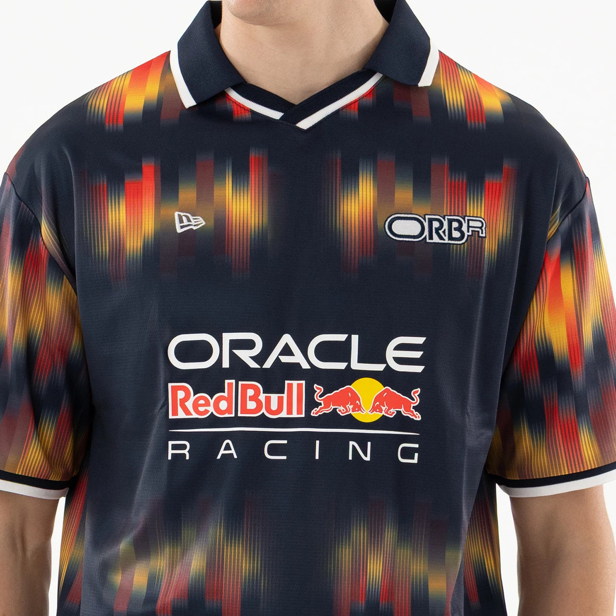 Red Bull Racing Multi Soccer Jersey, front view on a model with a striking pixelated pattern in red, yellow, and dark blue, featuring the New Era logo on the right chest and ORBR lettering on the left chest above Oracle Red Bull Racing branding.