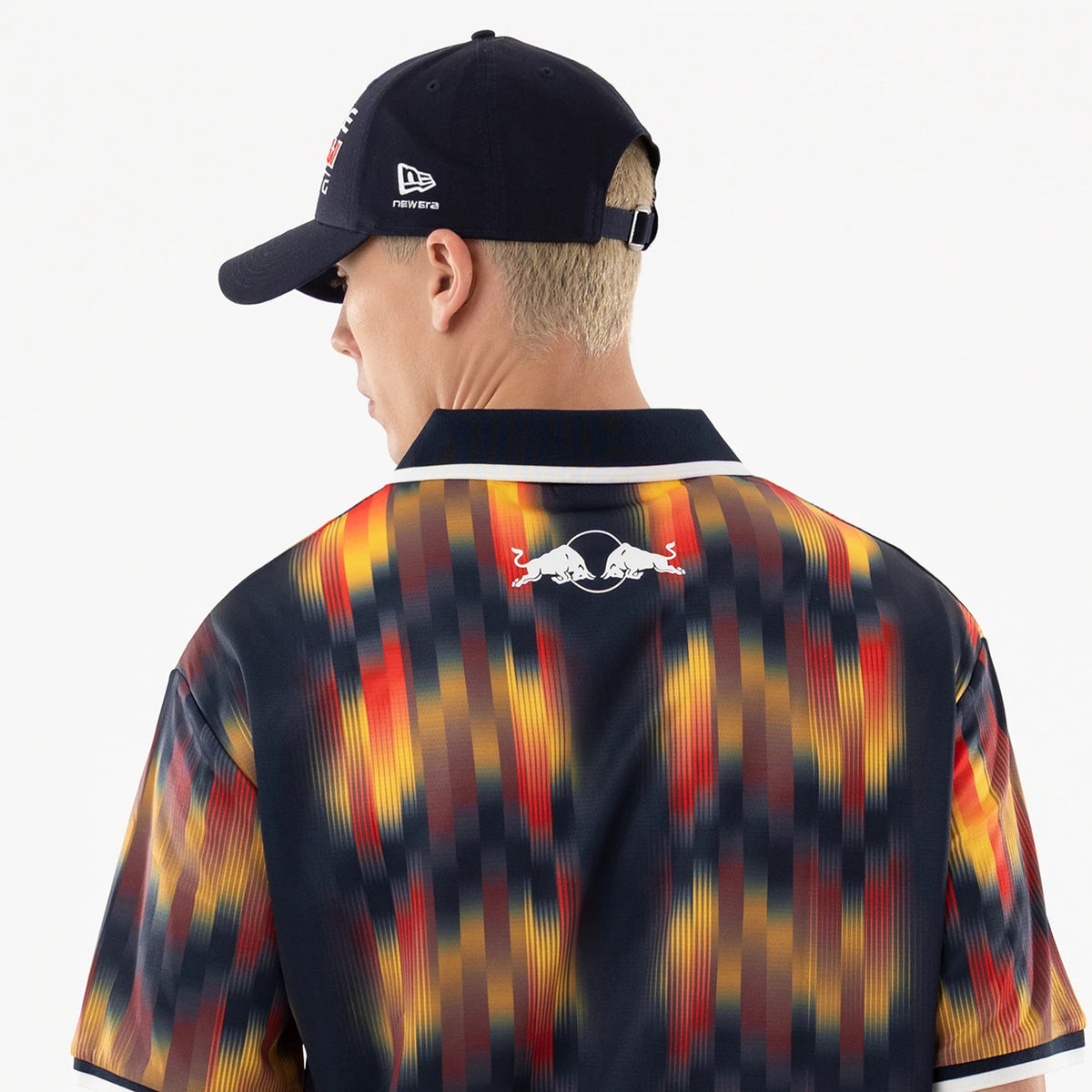 Red Bull Racing Multi Soccer Jersey, back view on a model wearing a dark cap with a New Era flag logo, showing a vibrant pattern with a white Red Bull logo at the top centre of the jersey.