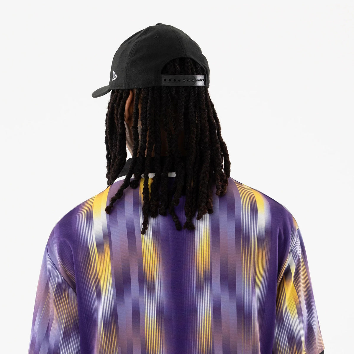 LA Lakers NBA Purple Soccer Jersey, back view on a model with a black cap, showcasing a gradient design of purple and yellow vertical stripes and a black collar with white detailing.