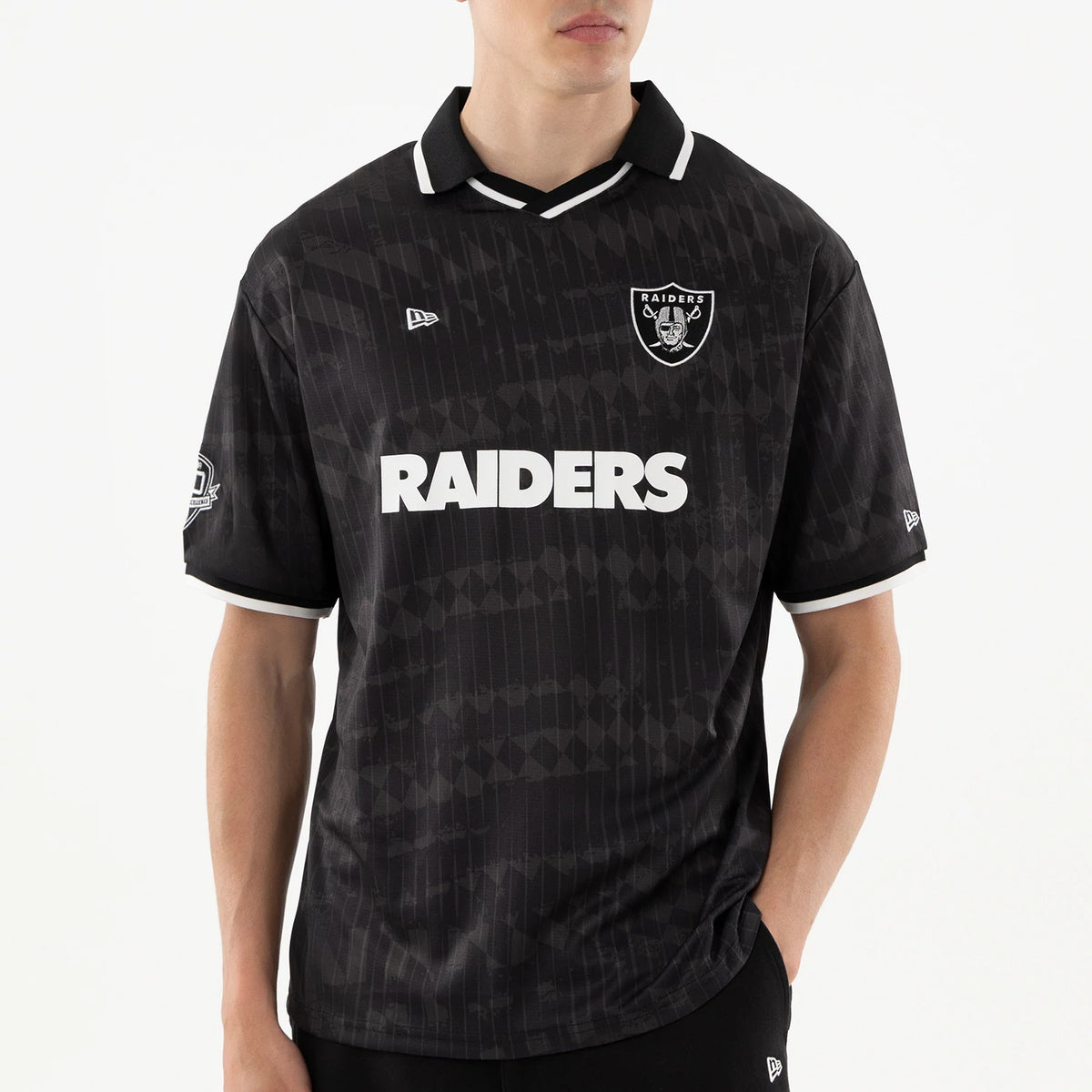 Las Vegas Raiders NFL Black Soccer Jersey, front view on a model showing the embroidered Raiders shield logo on the chest, prominent white RAIDERS lettering across the front, and New Era flag logo on the left chest and sleeve.