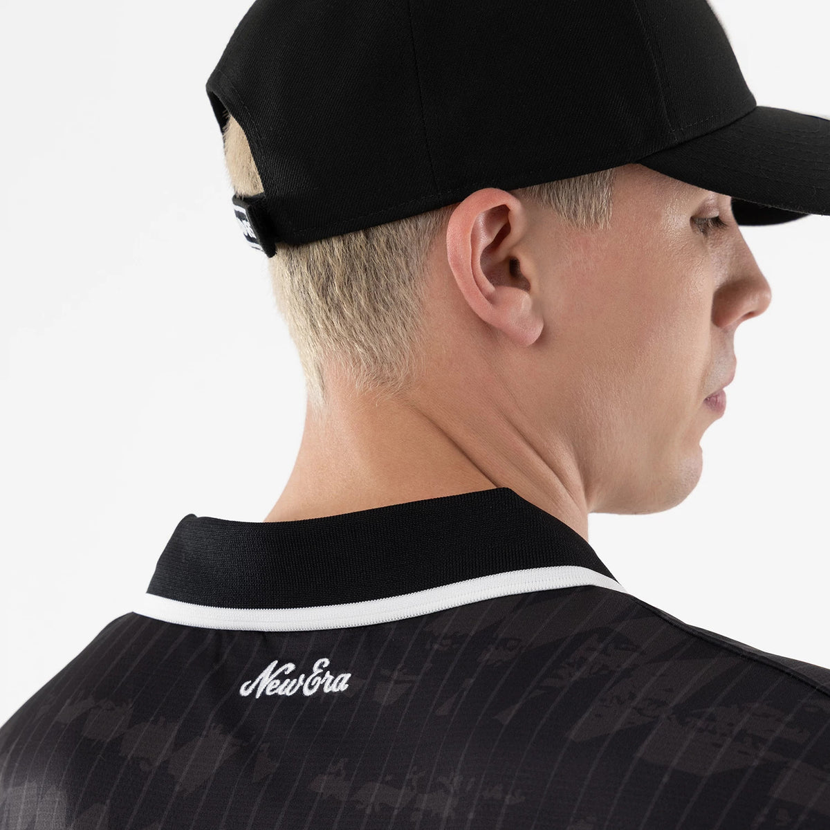 Las Vegas Raiders NFL Black Soccer Jersey, rear view on a model wearing a black cap, featuring a white New Era script logo on the upper back below a black collar with white trim detailing.